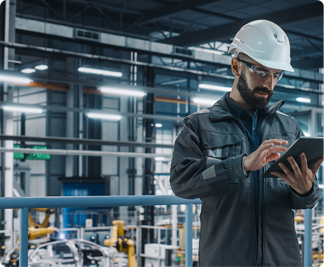 Man in hard hat using an ipad at a manufacturing plant